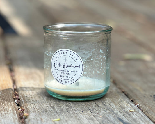 A recycled glass candle jar that has burned to the bottom of the glass. The scented candle was made by Sunset View and Rose. This image of a sustainable candle accompanies an article that offers tips on how to clean the wax out of a candle jar.